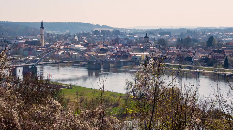 View of the Donau River and a bridge, in the background are houses and a church in Deggendorf.