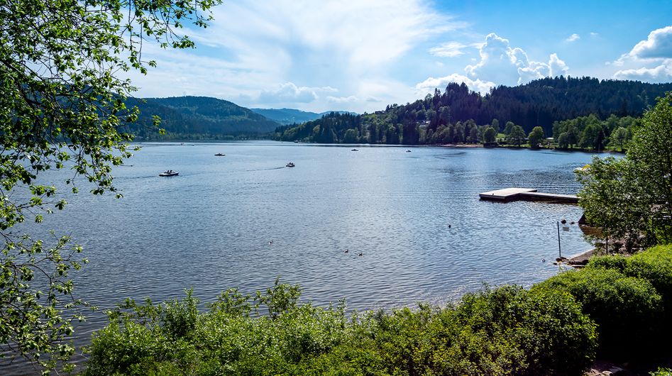 Lake with jetty and pedal boats, surrounded by green nature close to Furtwangen